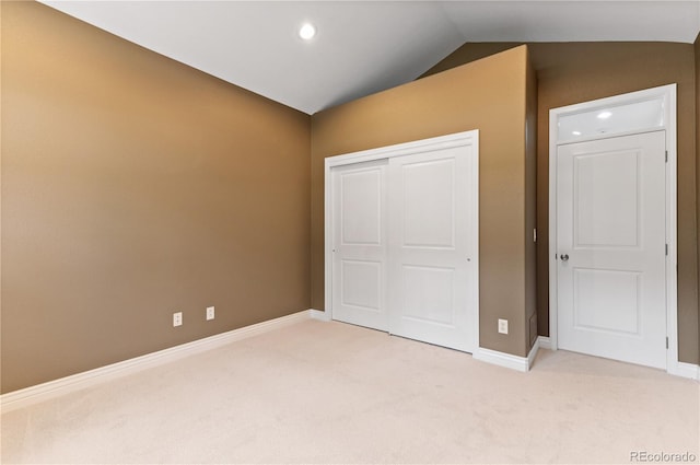 unfurnished bedroom featuring a closet, carpet floors, and vaulted ceiling