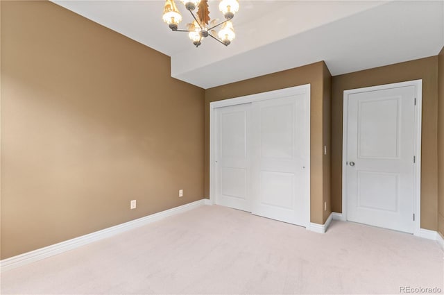 unfurnished bedroom with carpet floors, a closet, and an inviting chandelier