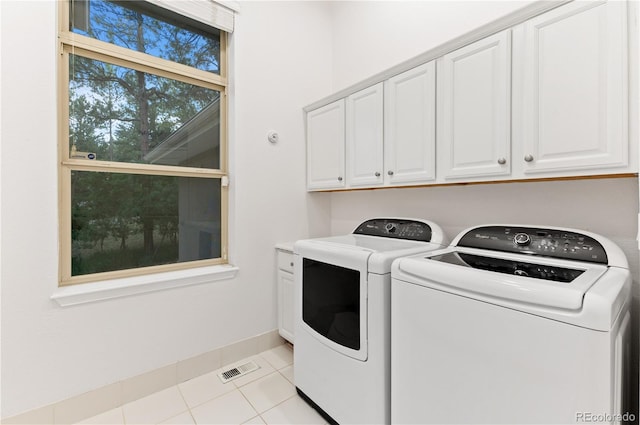 laundry area with light tile patterned flooring, washing machine and clothes dryer, and cabinets