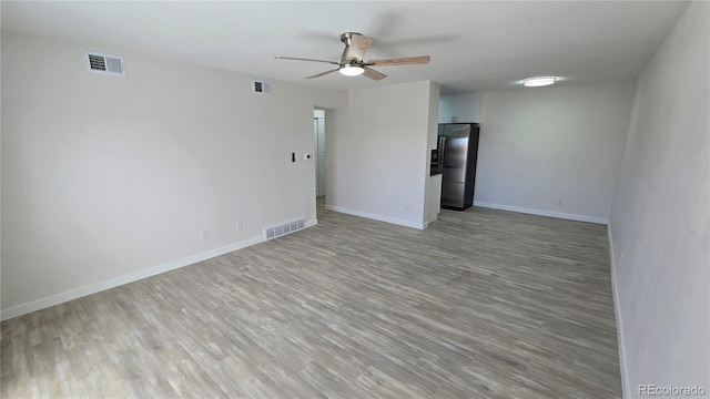 empty room featuring light wood-type flooring, visible vents, baseboards, and a ceiling fan