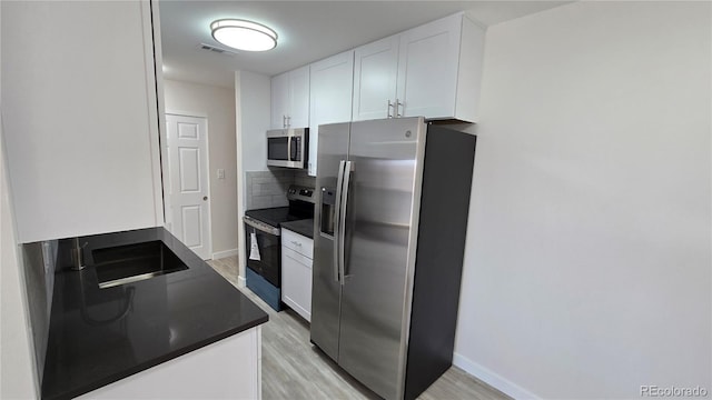 kitchen with dark countertops, visible vents, light wood-style floors, white cabinets, and stainless steel appliances