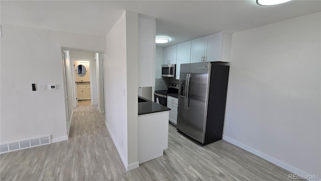 kitchen with visible vents, stainless steel appliances, light wood-style floors, white cabinetry, and dark countertops