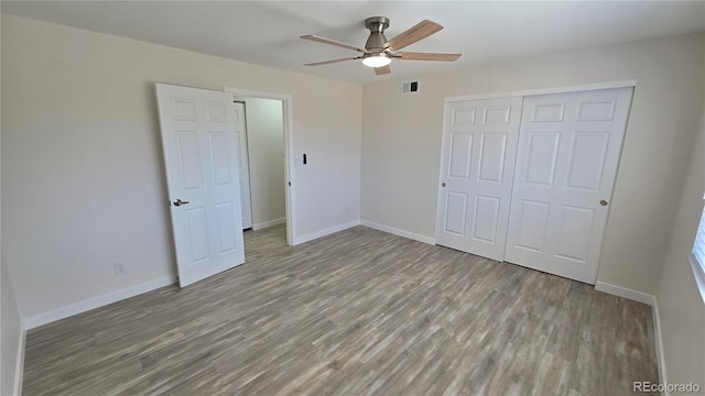 unfurnished bedroom featuring wood finished floors, visible vents, and baseboards