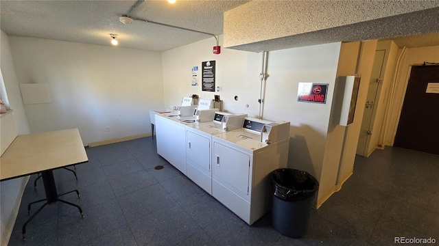 community laundry room featuring a textured ceiling, baseboards, and separate washer and dryer