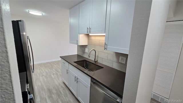 100 E Highline Cir Unit 307, Centennial, CO 80122 - kitchen with appliances with stainless steel finishes, decorative backsplash, dark countertops, light wood finished floors, and white cabinets