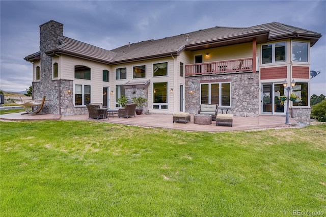13 Tamarade Dr, Littleton, CO 80127 - rear view of house with a chimney, stone siding, a lawn, and a balcony