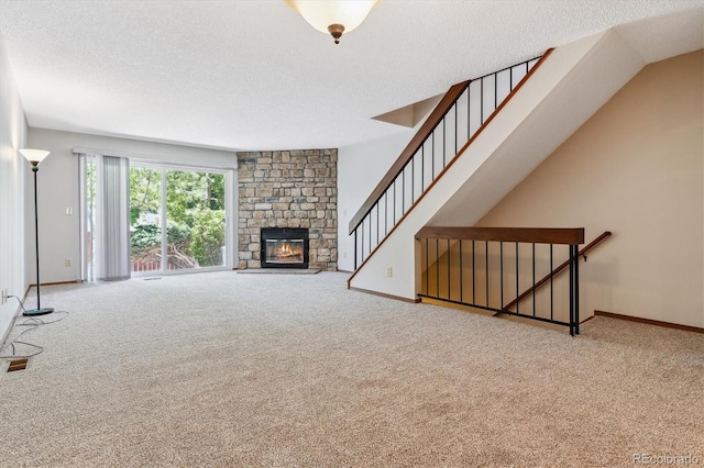 unfurnished living room with carpet flooring, a fireplace, baseboards, and a textured ceiling