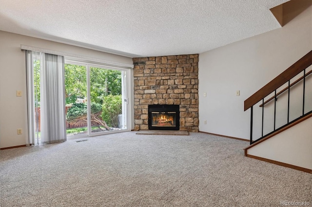 unfurnished living room featuring stairway, a textured ceiling, a fireplace, and carpet flooring