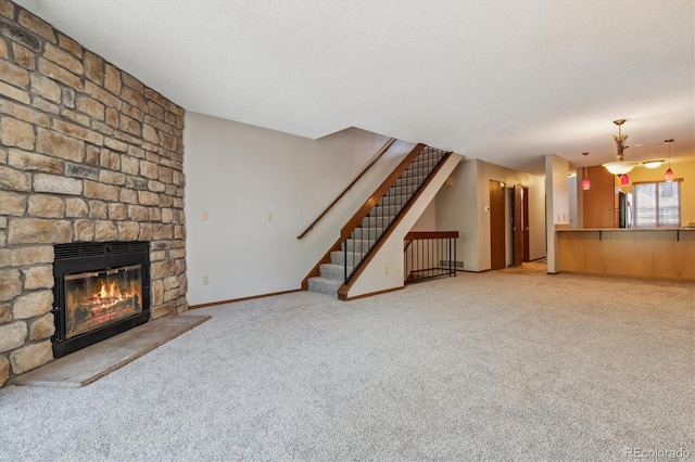 unfurnished living room with stairway, light carpet, a large fireplace, and a textured ceiling