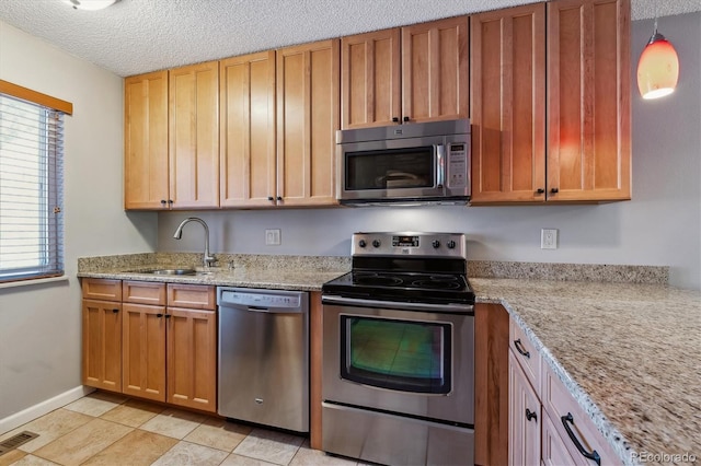 kitchen with visible vents, light stone countertops, appliances with stainless steel finishes, a textured ceiling, and a sink