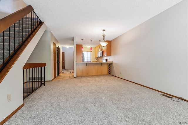 interior space with visible vents, light colored carpet, a textured ceiling, and baseboards