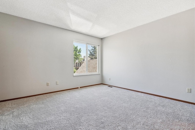 unfurnished room with visible vents, baseboards, a textured ceiling, and carpet flooring