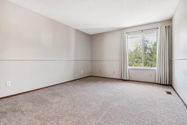 carpeted spare room featuring visible vents, a textured ceiling, and baseboards