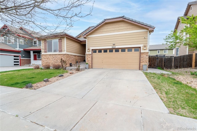 9844 Norfolk St, Commerce City, CO 80022 - view of front of property with driveway, stone siding, and a garage