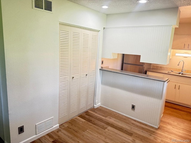 9255 E Lehigh Unit 213, Denver, CO 80237 - kitchen with fridge, light wood finished floors, recessed lighting, and a textured ceiling