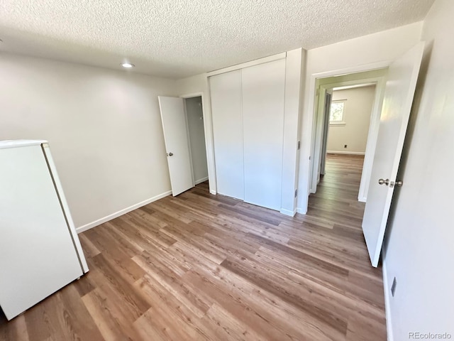 9255 E Lehigh Unit 213, Denver, CO 80237 - unfurnished bedroom featuring freestanding refrigerator, a textured ceiling, light wood-style floors, and a closet