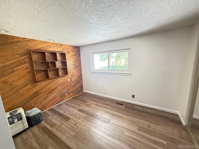 9255 E Lehigh Unit 213, Denver, CO 80237 - unfurnished bedroom featuring wood walls, a textured ceiling, and wood finished floors