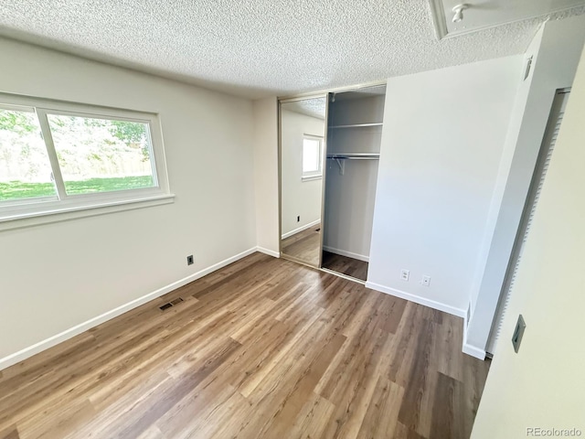 9255 E Lehigh Unit 213, Denver, CO 80237 - unfurnished bedroom featuring a textured ceiling, wood finished floors, multiple windows, and a closet