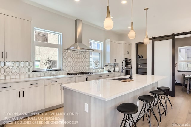 1768 Peak Loop, Broomfield, CO 80023 - kitchen featuring wall chimney exhaust hood, a breakfast bar, decorative backsplash, light countertops, and recessed lighting