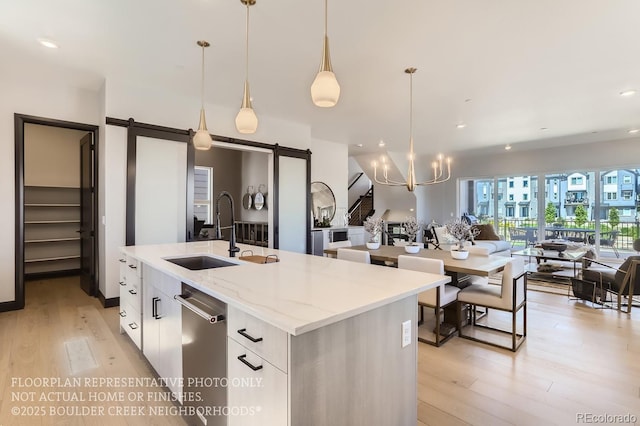 1768 Peak Loop, Broomfield, CO 80023 - kitchen with a barn door, open floor plan, light wood-style flooring, a kitchen island with sink, and dishwasher