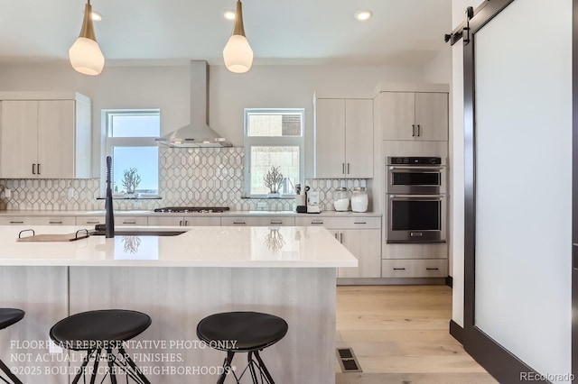 1768 Peak Loop, Broomfield, CO 80023 - kitchen with wall chimney range hood, appliances with stainless steel finishes, a breakfast bar, light countertops, and recessed lighting