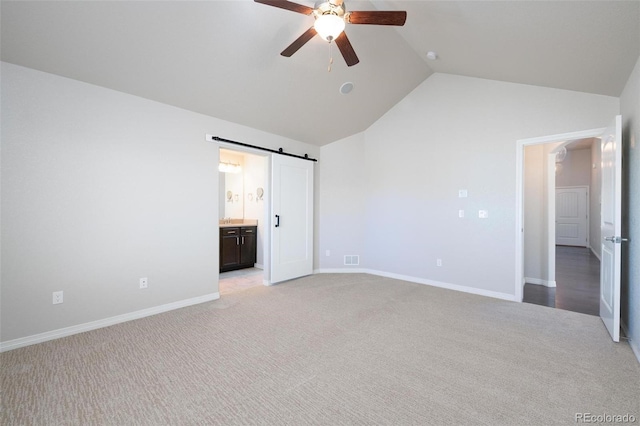 8230 Misty Moon Dr, Colorado Springs, CO 80924 - unfurnished bedroom featuring light carpet, vaulted ceiling, a barn door, connected bathroom, and baseboards
