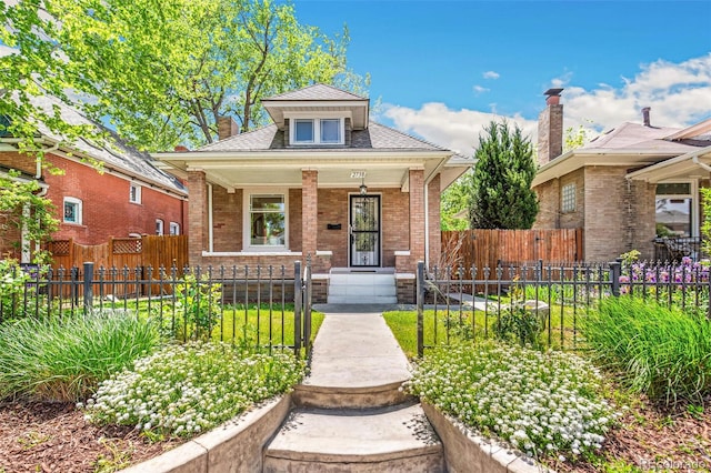 2738 W 38th Ave, Denver, CO 80211 - view of front of home with covered porch, a fenced front yard, a chimney, brick siding, and a shingled roof