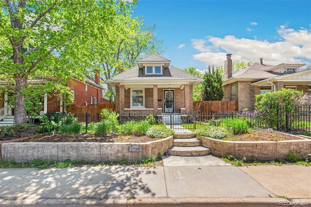 2738 W 38th Ave, Denver, CO 80211 - bungalow-style house featuring covered porch, a fenced front yard, brick siding, and roof with shingles