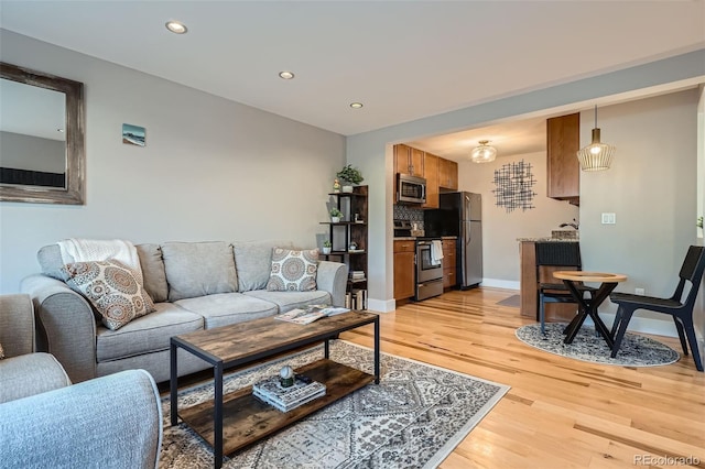 living area featuring recessed lighting, baseboards, and light wood finished floors