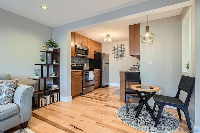 2460 W Caithness Pl Unit 104, Denver, CO 80211 - kitchen featuring appliances with stainless steel finishes, light wood finished floors, tasteful backsplash, brown cabinets, and recessed lighting