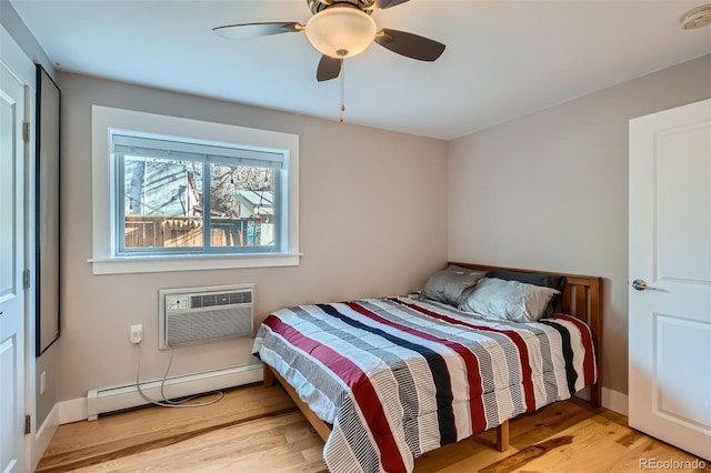 bedroom with ceiling fan, light wood-style flooring, baseboards, baseboard heating, and a wall mounted AC