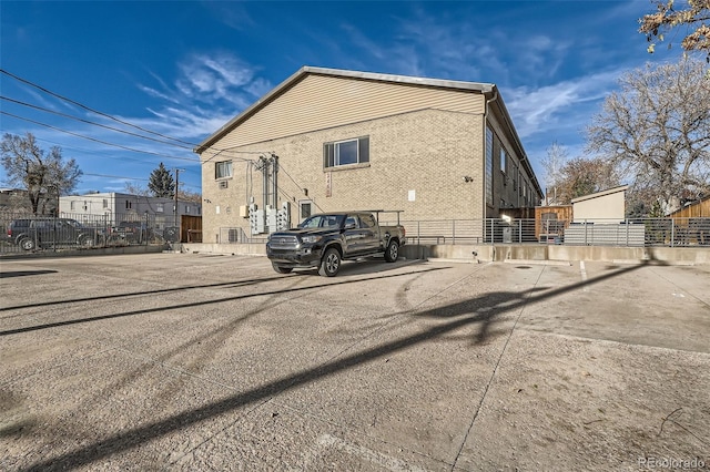 view of property exterior featuring fence and brick siding