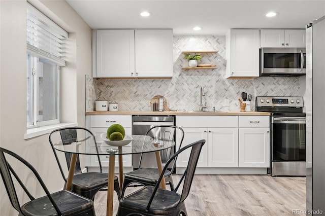 kitchen with white cabinetry, appliances with stainless steel finishes, butcher block counters, and sink