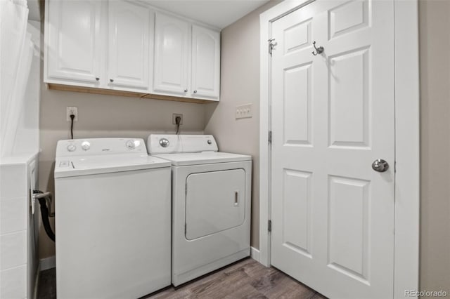 laundry room featuring hardwood / wood-style flooring, washing machine and dryer, and cabinets