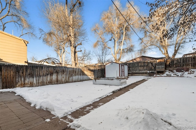 yard covered in snow featuring a storage shed