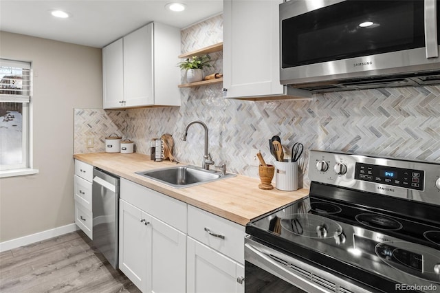 3024 S Sherman St, Englewood, CO 80113 - kitchen with appliances with stainless steel finishes, a sink, white cabinets, decorative backsplash, and recessed lighting