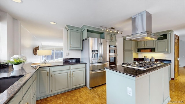 kitchen with appliances with stainless steel finishes, island range hood, a kitchen island, light parquet floors, and dark stone countertops