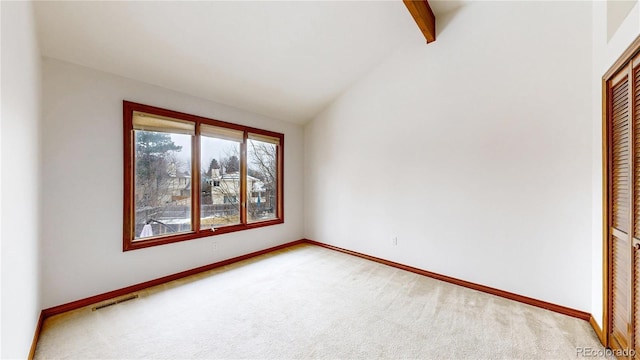 carpeted spare room with lofted ceiling