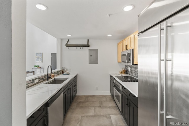 kitchen with tasteful backsplash, electric panel, appliances with stainless steel finishes, light brown cabinets, and a sink