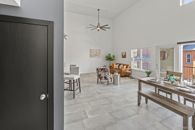 dining area featuring ceiling fan, a high ceiling, and baseboards