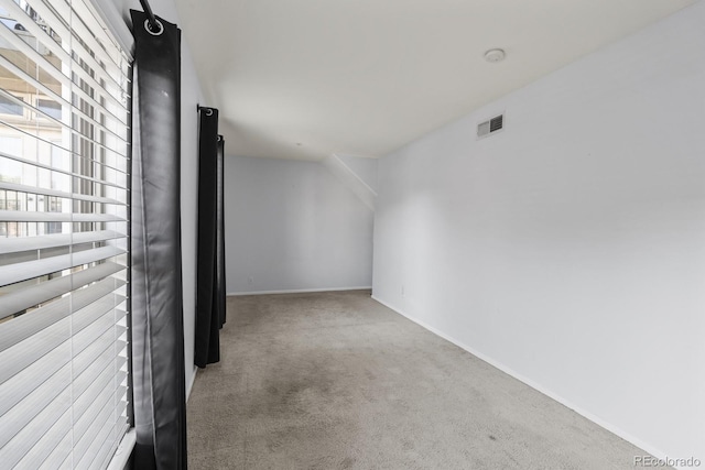 carpeted spare room with visible vents and baseboards