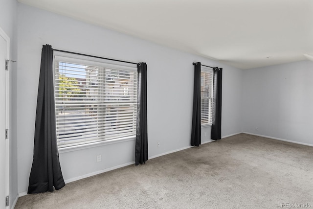 carpeted empty room featuring baseboards