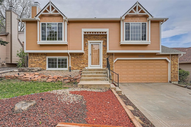 raised ranch with concrete driveway, brick siding, and an attached garage