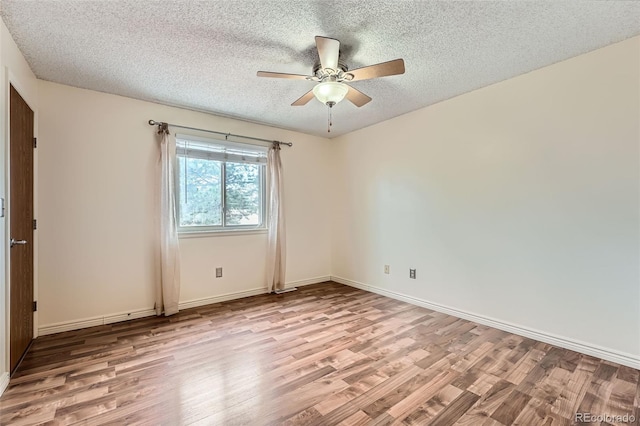 empty room with a textured ceiling, baseboards, a ceiling fan, and wood finished floors