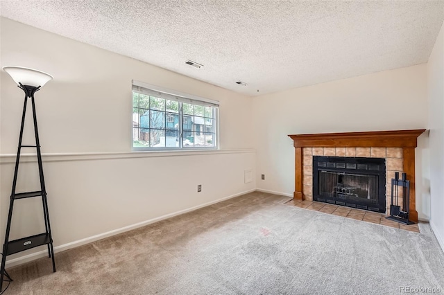 unfurnished living room featuring carpet flooring, a tiled fireplace, visible vents, and a textured ceiling