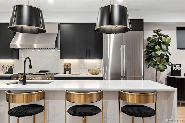3709 Tejon St, Denver, CO 80211 - kitchen featuring dark cabinetry, freestanding refrigerator, wall chimney range hood, a kitchen breakfast bar, and decorative backsplash