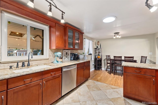 kitchen featuring a wealth of natural light, sink, decorative backsplash, stainless steel dishwasher, and light stone countertops