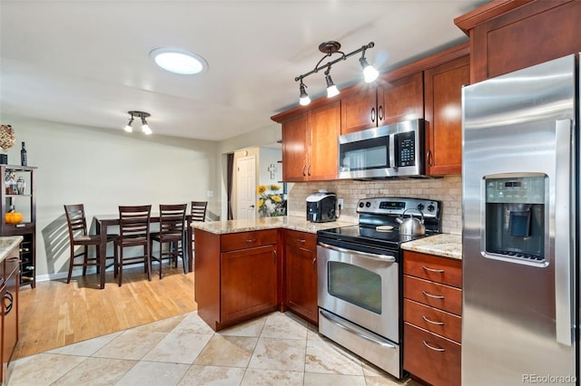 kitchen featuring tasteful backsplash, appliances with stainless steel finishes, light stone counters, and light tile patterned floors