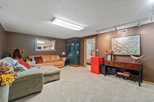 carpeted living room featuring track lighting and a textured ceiling