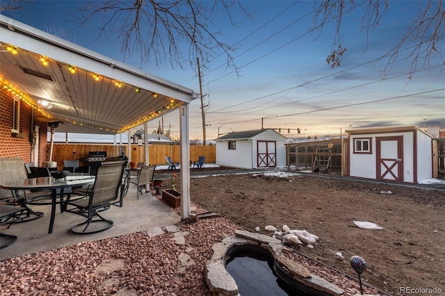 yard at dusk featuring a storage shed and a patio area